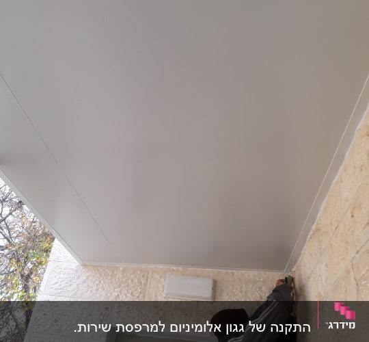 אדם מתקין תקרה מאלומיניום עם כלי עבודה